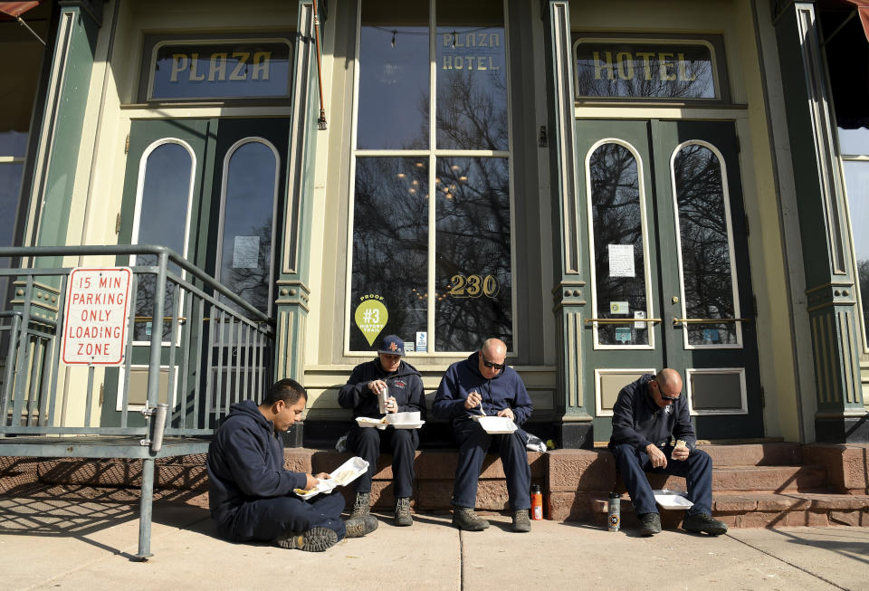 A group of firefighters from Apple Valley, Calif., eat breakfast outside the historic Plaza Hotel in downtown Las Vegas, New Mexico, on Wednesday, May 4, 2022. Firefighters from all over the country have converged on the small community to battle a wildfire that has burned 250 square miles (647 square kilometers). (AP Photo/Thomas Peipert)