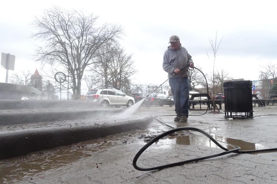 Jerry Moore pressure washes the sidewalk Friday outside his boss' building downtown Mansfield.