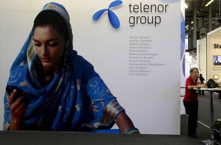 A visitor rests under a Telenor Group sign at the GSMA Mobile World Conference in Barcelona February 18, 2009. REUTERS/Gustau Nacarino/File Photo