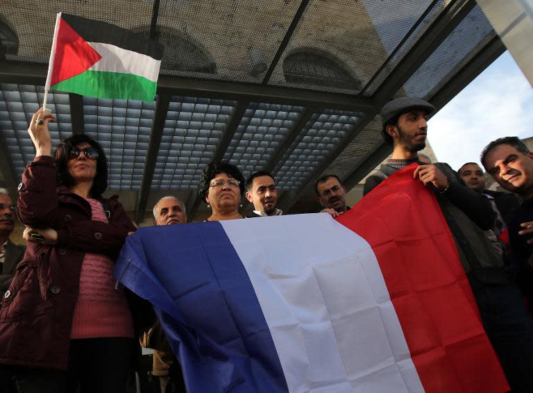 Palestinians wave French and Palestinian flags during a rally in the West Bank city of Ramallah, on December 2, 2014