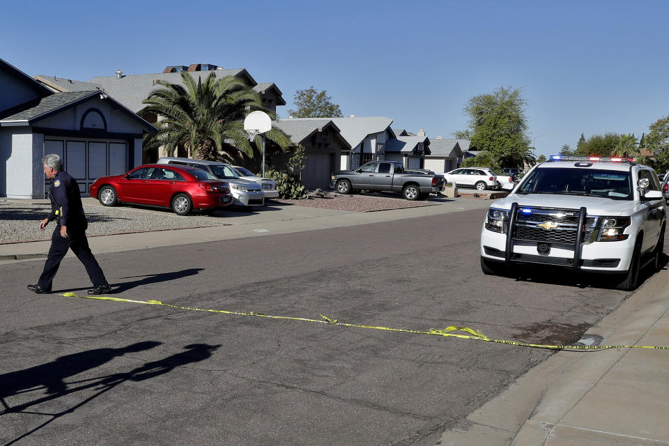 A Phoenix police officer lays out crime scene tape outside the scene of a deadly shooting early Monday, March 30, 2020, in Phoenix. Phoenix police say one of their commanders was killed and two other officers were wounded as they responded to a domestic dispute. Authorities say Cmdr. Greg Carnicle and officers were called to a home in the northern part of Phoenix Sunday night over a roommate dispute when the suspect refused to cooperate and shot them. The suspect was not identified and was pronounced dead at the scene. (AP Photo/Matt York)