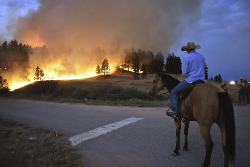 FILE - Rowdy Alexander watches from atop his horse as a hillside burns on the Northern Cheyenne Indian Reservation on Aug 11, 2021, near Lame Deer, Mont. An area outside Denver where Colorado's most destructive in history wildfire burned 1,000 homes last month is home to numerous abandoned coal mines that authorities say could be a potential cause of the wind-driven wildfire. This past summer in Montana, smoldering coal seams were blamed for a string of major fires that burned hundreds of square miles and prompted widespread evacuations. (AP Photo/Matthew Brown, File)