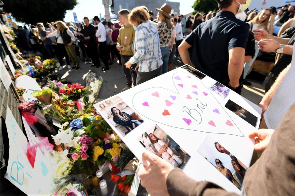 A person holds a poster board with photos.