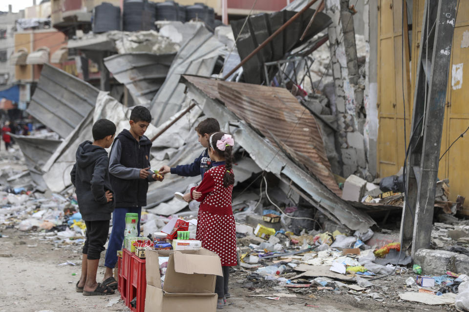 Palestinian children sell sweets in front of the rubble of a destroyed building in Jebaliya refugee camp, Gaza Strip, Tuesday, Nov. 28, 2023, on the fifth day of the temporary ceasefire between Hamas and Israel. (AP Photo/Mohammed Hajjar)