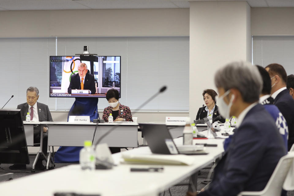 IOC President Thomas Bach, on the screen, speaks remotely during an on-line meeting focused on how to pull off the delayed Tokyo Games, in Tokyo, Thursday, Sept. 24, 2020. Bach delivered a pep talk to Japanese government officials and local organizers on Thursday that included suggestions that “hundreds of millions”of doses COVID-19 vaccines would be available before the postponed Olympic are to open on July 23, 2021. (Du Xiaoyi/Pool Photo via AP)