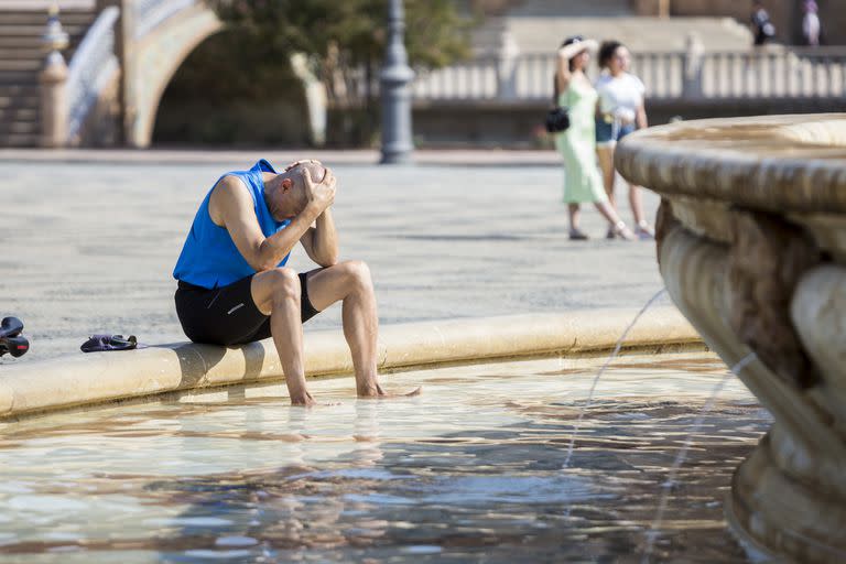 Un hombre busca refrescarse en la fuente de la Plaza de España, en Sevilla. Photo: Daniel Gonzalez Acuna/dpa