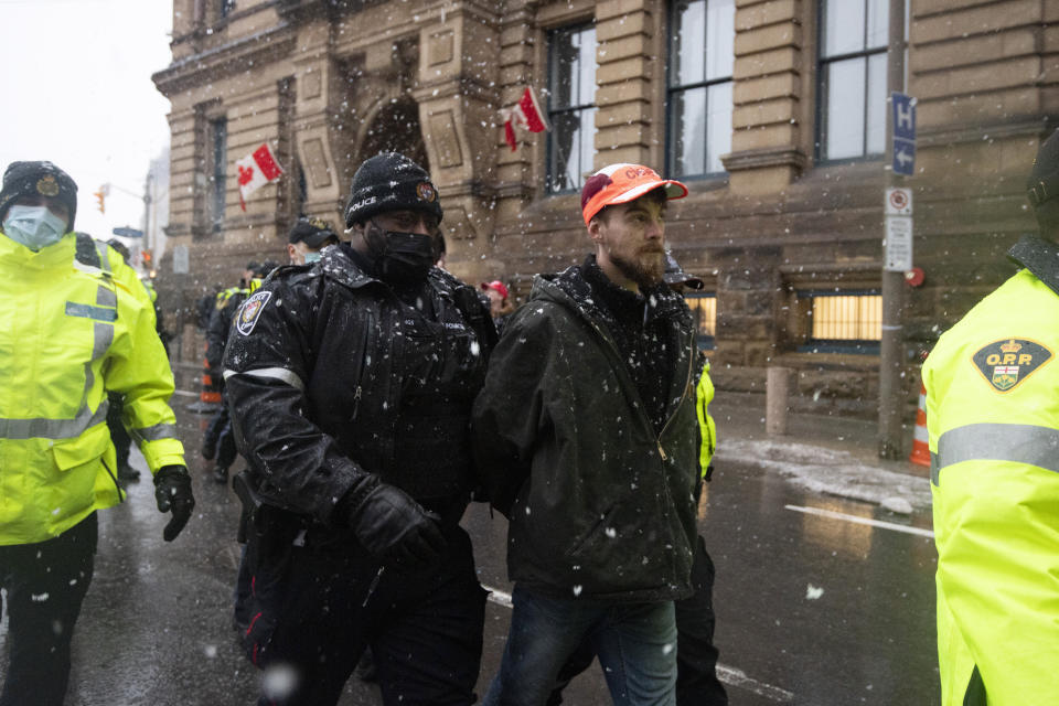 Police lead a protester towards a cruiser after making an arrest on Wellington Street, during an ongoing protest against COVID-19 measures that has grown into a broader anti-government protest, in Ottawa, Ontario, on Thursday, Feb. 17, 2022. (Justin Tang/The Canadian Press via AP)