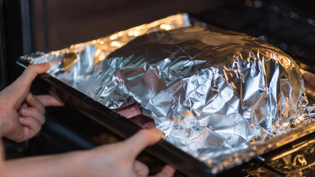 A woman putting raw beef on the oven