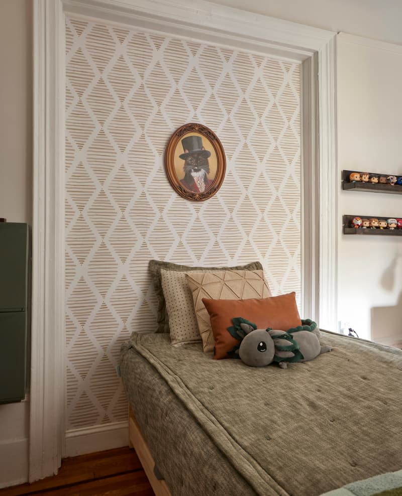 Animal portrait art on wallpapered section of wall bordered by crown moulding behind bed.