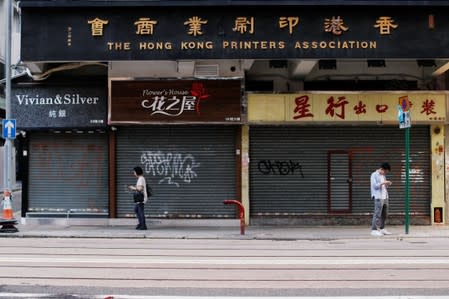 People are seen in front of closed stores in Wan Chai district, in Hong Kong