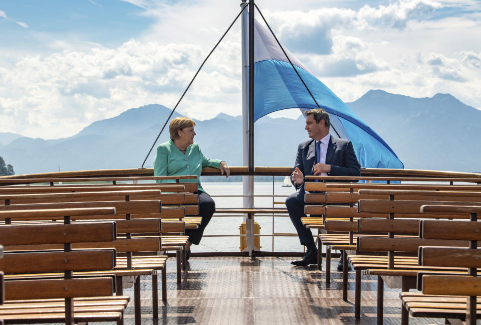 FILE - In this Tuesday, July 14, 2020 file photo, German Chancellor Angela, left, and Markus Soeder, right, Governour of the German state of Bavaria, talk during a boat tour in Priem Am Chiemsee, Germany. Markus Soeder is many things: state governor of Bavaria, Star Trek fan, a conservative for whom combating climate change is an article of faith. The question Germans are asking now is: can the 54-year-old win enough backing across the political spectrum to succeed Angela Merkel as chancellor in September. (Peter Kneffel/DPA via AP, Pool, file)