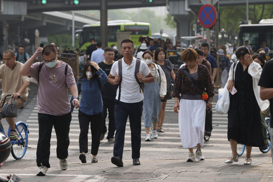 Pedestrians cross an intersection at the central business district in Beijing, China, Monday, July 15, 2024. China's ruling Communist Party is starting a four-day meeting Monday that is expected to lay out a strategy for self-sufficient economic growth in an era of heightened national security concerns and restrictions on access to American technology. (AP Photo/Vincent Thian)