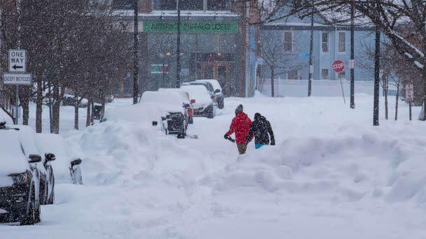 PHOTO: People move about the streets of the Elmwood Village neighborhood of Buffalo, N.Y., Monday, Dec. 26, 2022, after a massive snow storm blanketed the city. Along with drifts and travel bans, many streets were impassible due to abandoned vehicles. (Craig Ruttle/AP)