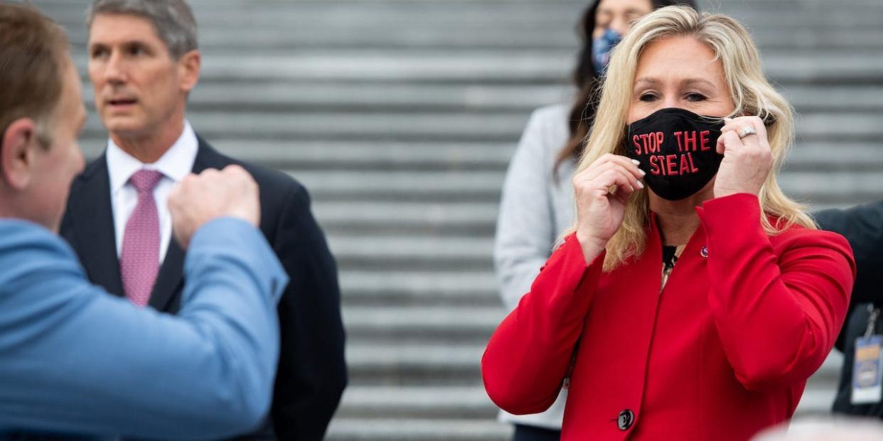 Rep. Marjorie Taylor Greene, Republican of Georgia, holds up a "Stop the Steal" mask while speaking with fellow first-term Republican members of Congress on the steps of the US Capitol in Washington, DC, January 4, 2021.