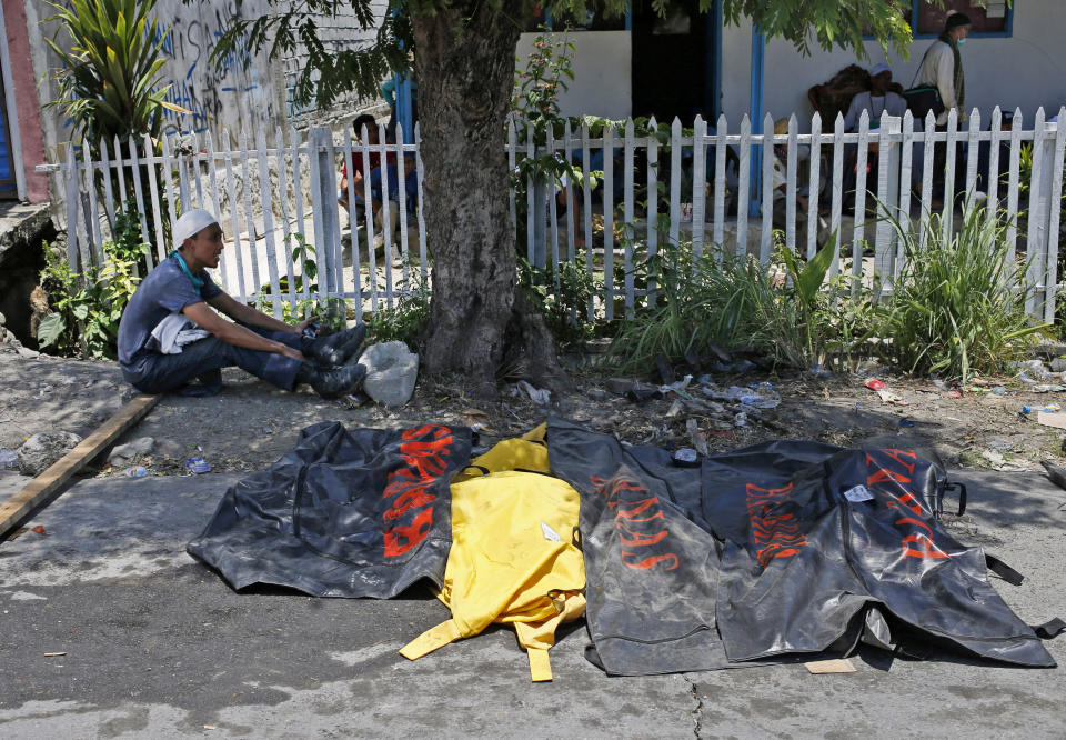 In this Oct. 2, 2018, photo, a Muslim volunteer of the humanitarian wing of the Islamic Defenders Front takes a break near body bags containing the remains of the earthquake and liquefaction victims recovered from the rubble of Balaroa neighborhood in Palu, Central Sulawesi, Indonesia Indonesia. Indonesia's Islamic Defenders Front is better known for vigilante actions against gays, Christmas decorations and prostitution, but over the past decade and a half it has repurposed its militia into a force that's as adept at searching for victims buried under earthquake rubble and distributing aid as it is at inspiring fear. (AP Photo/Dita Alangkara)