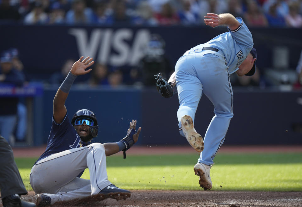 Tampa Bay Rays' Junior Caminero, left, slides ahead of a tag by Toronto Blue Jays starting pitcher Wes Parsons, right, during second-inning baseball game action in Toronto, Sunday, Oct. 1, 2023. (Frank Gunn/The Canadian Press via AP)