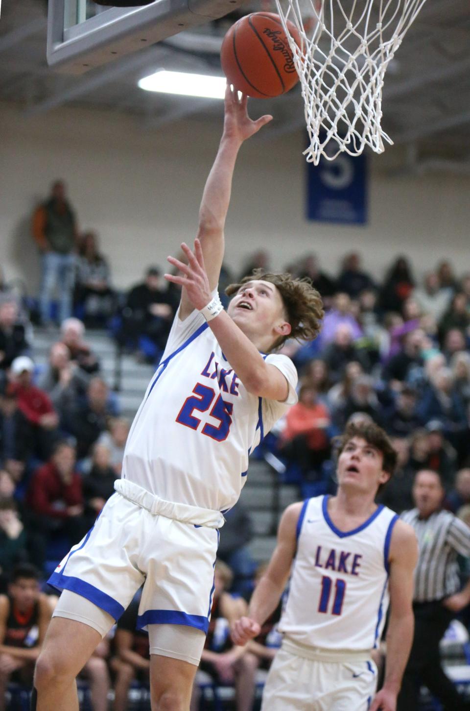 Chance Casenhiser, 25, of Lake goes to the basket as Camden Horning, 11, looks on during their game against Green at Lake on Tuesday, Jan. 25, 2022.