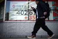 A person walks in front of an electronic stock board showing Japan's Nikkei 225 index at a securities firm Monday, March 4, 2024, in Tokyo. Japan's Nikkei 225 share benchmark has topped 40,000 for the first time as strong demand for technology shares keeps pushing the index higher. (AP Photo/Eugene Hoshiko)