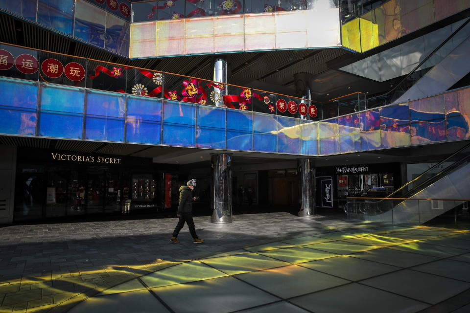 FILE - In this Feb. 10, 2020, file photo, a masked man walks by a quiet shopping mall during a lunch hours in Beijing. Chinese authorities are struggling to strike a delicate balance between containing a deadly viral outbreak and restarting the world’s second-biggest economy after weeks of paralysis. (AP Photo/Andy Wong, File)