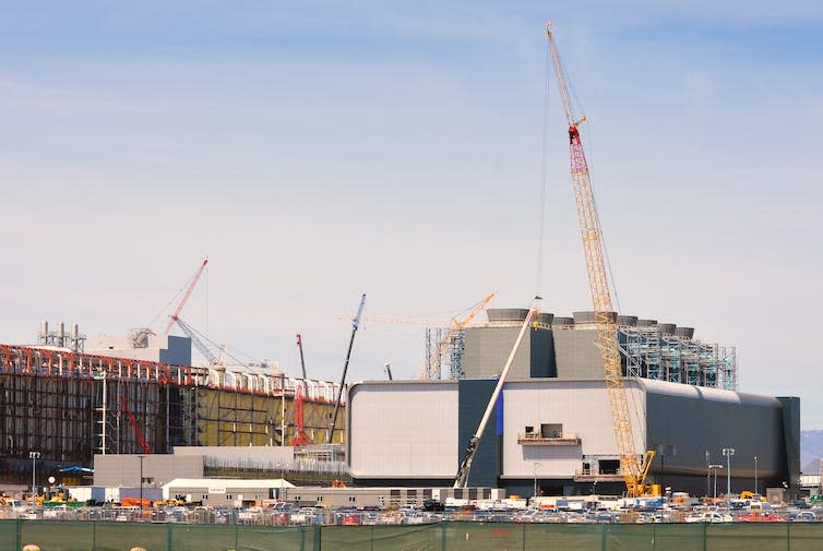 A large factory under construction on a clear, sunny day.