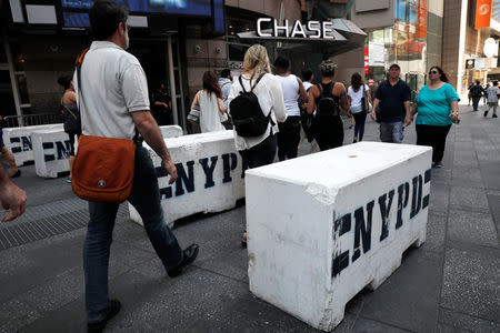 People walk between newly erected concrete barricades outside the 3 Times Square building in Times Square where a speeding vehicle struck pedestrians Thursday in New York City, U.S., May 19, 2017. REUTERS/Mike Segar