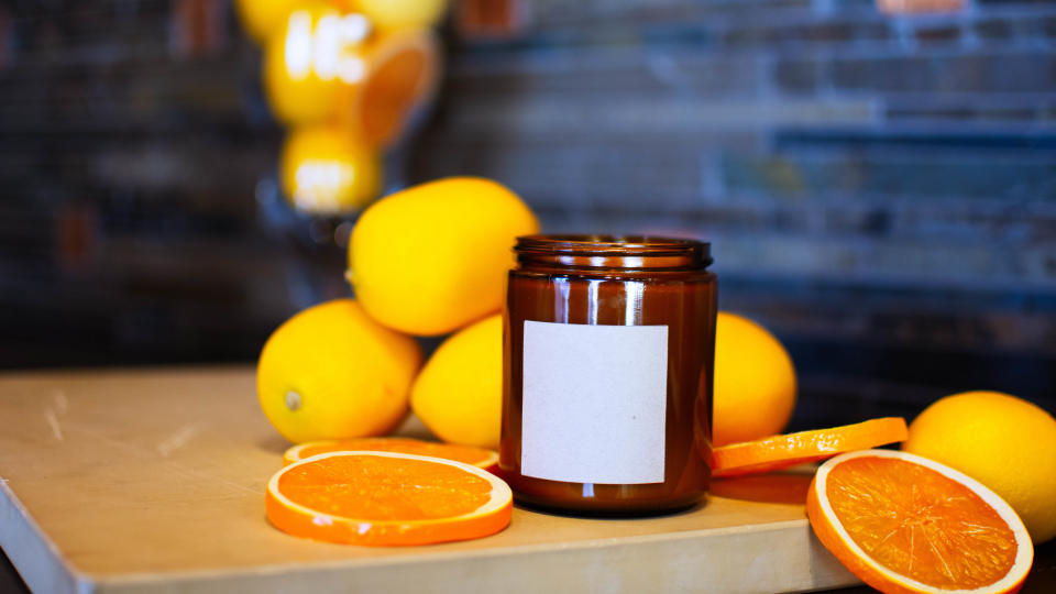 A candle surrounded with oranges and citrus fruits