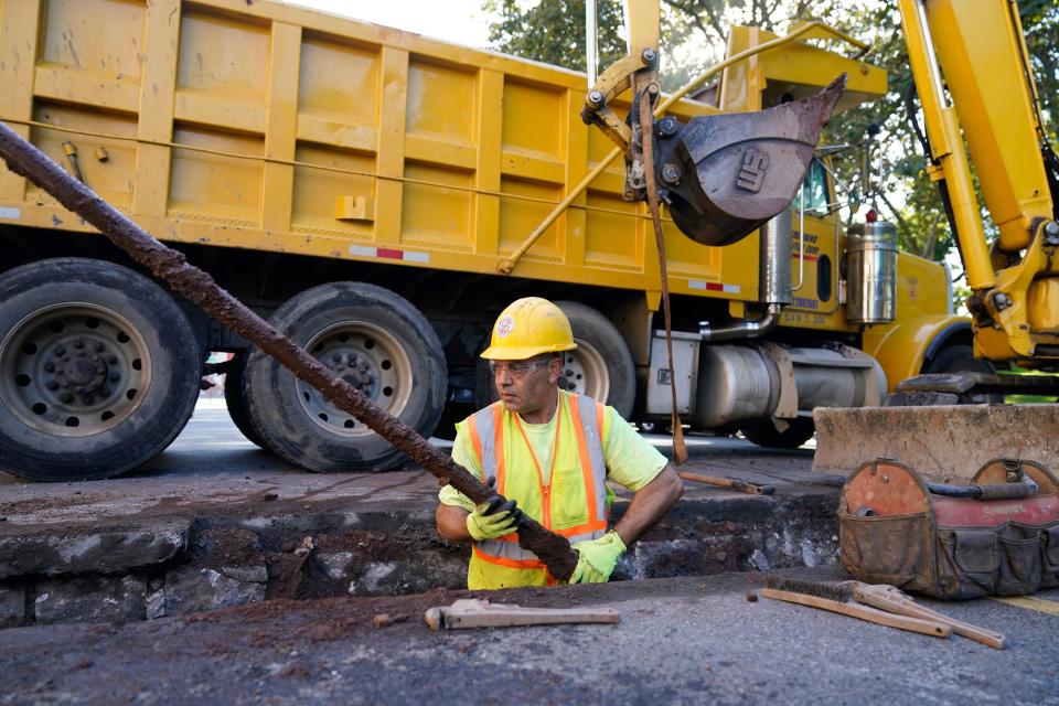 A worker removes an old water pipe from underneath the street before replacing it with new copper pipe in Newark, N.J., Thursday, Oct. 21, 2021.