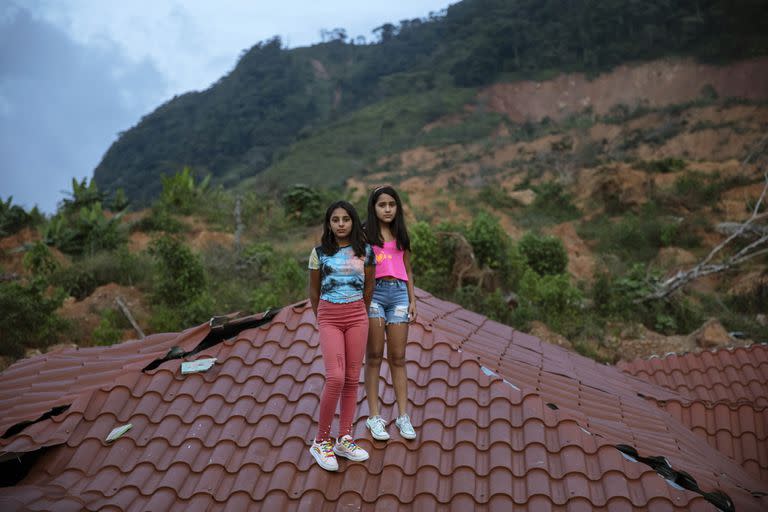 Las gemelas Dulce Alejandra Mejía, y Genesis Mejía, de 12 años, posan sobre el techo de la casa de su vecino devastada por los huracanes en el poblado de La Reina. Sus padres viven en España