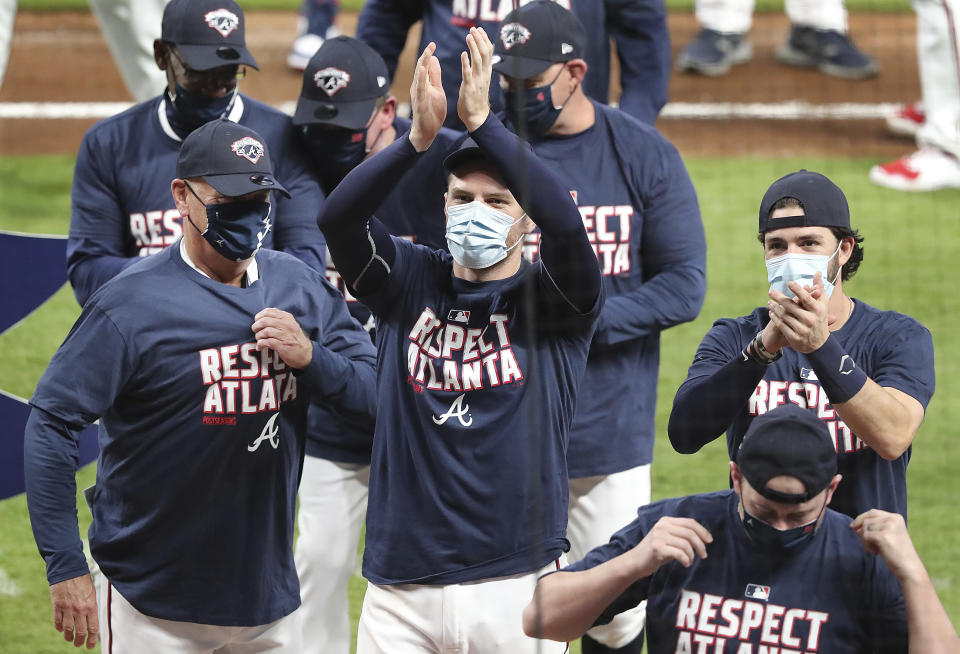 From left, Atlanta Braves manager Brian Snitker, Freddie Freeman, and Dansby Swanson celebrate clinching their third consecutive National League East championship title with a victory over the Miami Marlins in a baseball game on Tuesday, Sept. 22, 2020, in Atlanta. (Curtis Compton/Atlanta Journal-Constitution via AP)