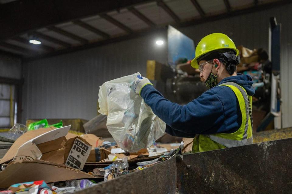 A GFL employee manually separates plastic bags from piles of recycling materials at the GFL Materials Recovery Facility on Tuesday, March 28, 2023, in Harrisonville, Mo. GFL does not accept plastic bags at its facility.