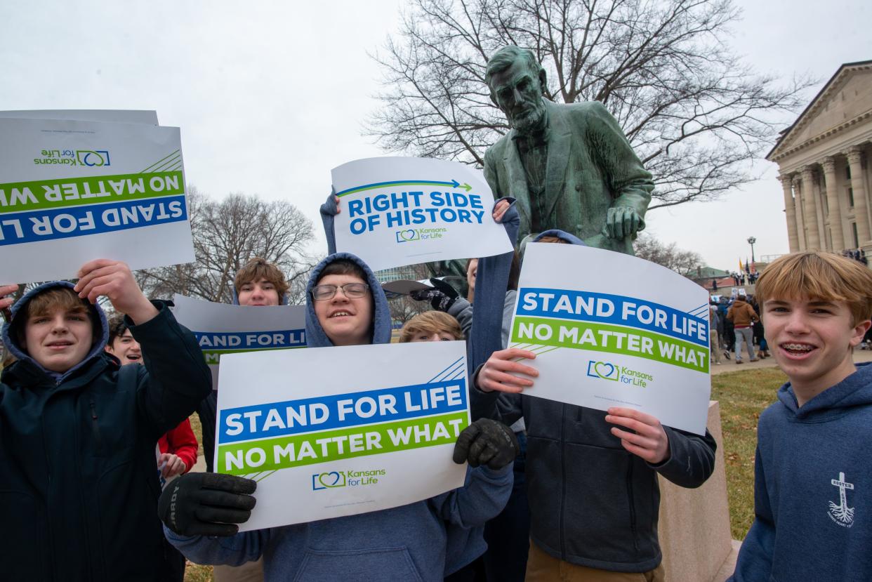 Signs from Kansans for Life are held by young anti-abortion activists in front of a statue of Abraham Lincoln during January's March for Life event at the Kansas Statehouse. Kansans for Life and other anti-abortion groups are pushing to redefine abortion in state law.