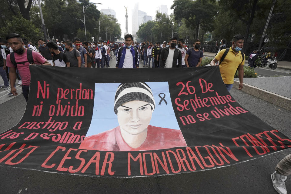 Supporters and relatives of 43 missing university students hold a banner with the likeness of one of the missing students, as they march on the seventh anniversary of their disappearance, in Mexico City, Sunday, Sept. 26, 2021. Relatives continue to demand justice for the Ayotzinapa students who were allegedly taken from the buses by the local police and handed over to a gang of drug traffickers. (AP Photo/Marco Ugarte)