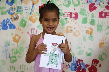 Yonaily Figuera, 4, holds a drawing she drew which depicts the late Venezuelan President Hugo Chavez, during a writing workshop at 4F military fort in Caracas December 14, 2014. REUTERS/Carlos Garcia Rawlins