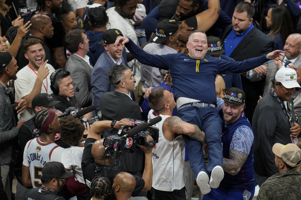 El entrenador de los Nuggets de Denver Michael Malone es alzado tras conquistar el campeonato de la NBA al vencer al Heat de Miami en el quinto juegos de la Finales, el lunes 12 de junio de 2023, en Denver. (AP Foto/David Zalubowski)