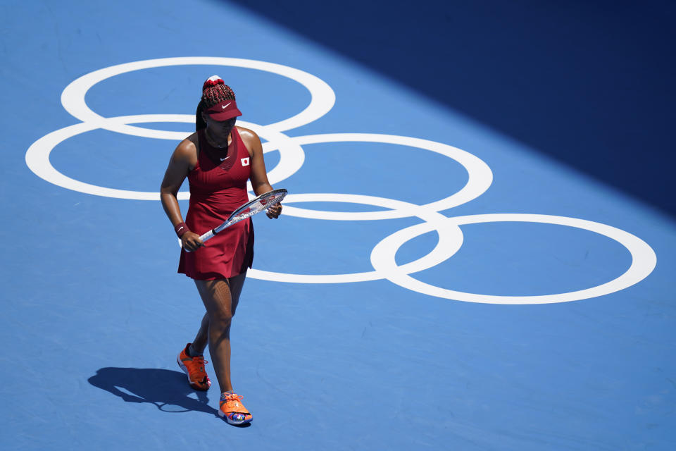 FILE - In this July 25, 2021 file photo Naomi Osaka, of Japan, inspects her racket during a tennis match against China's Zheng Saisai at the 2020 Summer Olympics, in Tokyo, Japan. Osaka and Simone Biles are prominent young Black women under the pressure of a global Olympic spotlight that few human beings ever face. But being a young Black woman -- which, in American life, comes with its own built-in pressure to perform -- entails much more than meets the eye. (AP Photo/Patrick Semansky, File)