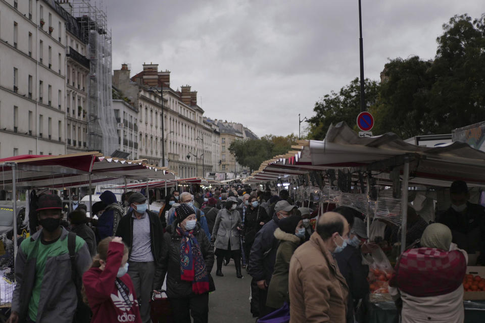 People wearing protective face masks as precaution against the conoravirus shop at an outdoor market in Paris, Friday, Oct. 30, 2020. France re-imposed a monthlong nationwide lockdown Friday aimed at slowing the spread of the virus, closing all non-essential business and forbidding people from going beyond one kilometer from their homes except to go to school or a few other essential reasons. (AP Photo/Thibault Camus)