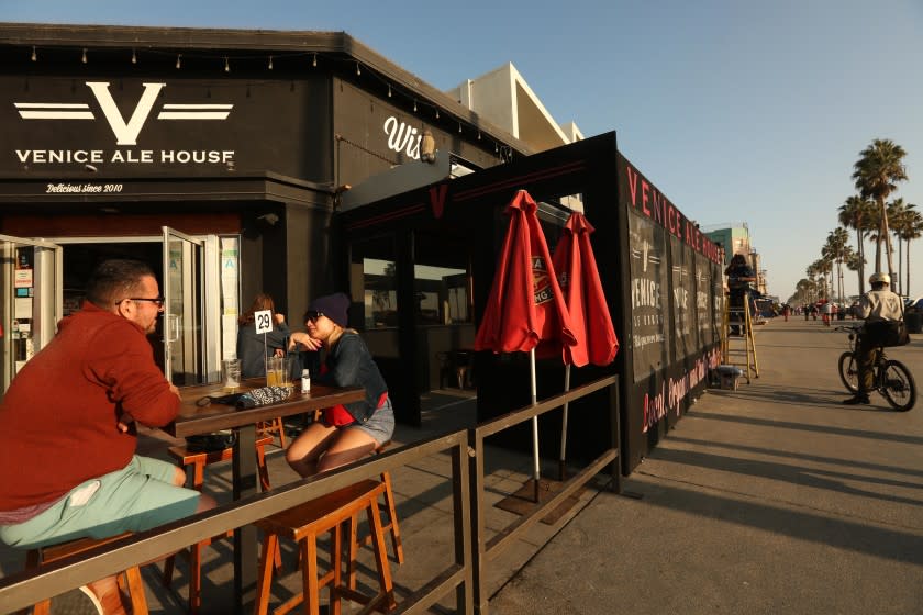 VENICE, CA - NOVEMBER 23, 2020 - Raul and Silvia Garcia enjoy a beer at the Venice Ale House along Ocean Front Walk in Venice on November 23, 2020. "Leave them open," Raul said about the closing of open air dining in L.A. County. "I can understand inside, but right here. What difference does it make," he concluded. In a devastating blow to Los Angeles' struggling restaurant and hospitality industry, L.A. County public health officials on Sunday announced they will suspend outdoor dining at restaurants amid a surge of new coronavirus cases.The new rule takes effect at 10 p.m. Wednesday and restricts restaurants - along with breweries, wineries and bars - to takeout and delivery only for the first time since May. Venice on Monday, Nov. 23, 2020 Venice, CA. (Genaro Molina / Los Angeles Times)