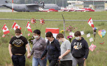 The Canadian Forces Snowbirds jets are seen in the background as a family pays their respects at the Kamloops airport in Kamloops, British Columbia, Monday, May 18, 2020. Capt. Jennifer Casey died Sunday after the Snowbirds jet she was in crashed shortly after takeoff. The pilot of the aircraft is in hospital with serious injuries. (Jonathan Hayward/The Canadian Press via AP)