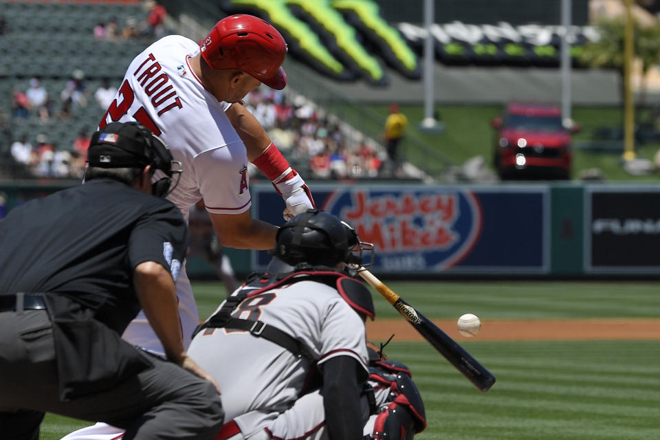 Los Angeles Angels' Mike Trout, center, hits a solo home run as Arizona Diamondbacks catcher Carson Kelly, right, watches along with home plate umpire Doug Eddings during the first inning of a baseball game Sunday, July 2, 2023, in Anaheim, Calif. (AP Photo/Mark J. Terrill)