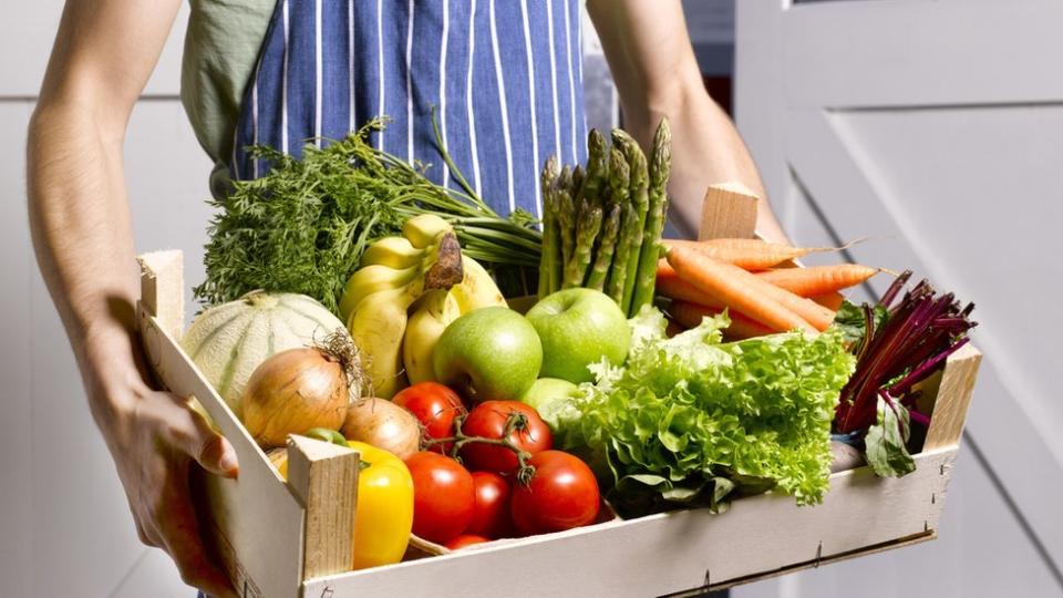 Hombre con cesta de frutas y verduras.