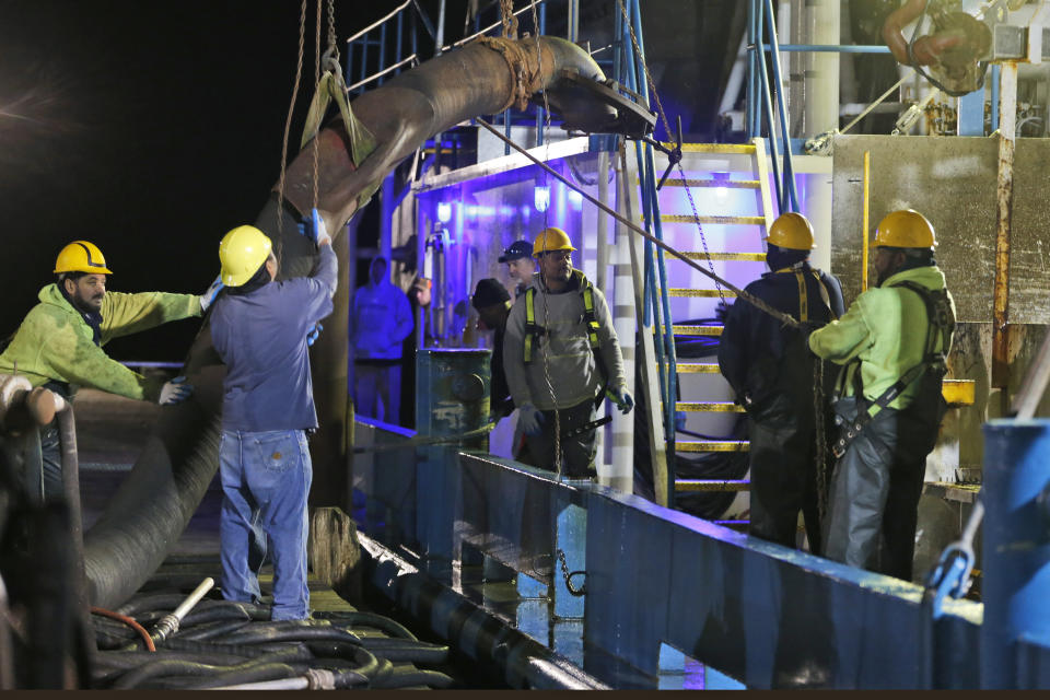 Workers prepare to attach suction hose to the menhaden fishing boat Windmill Point at Omega Protein's menhaden processing plant on Cockrell's Creek in Reedville, Va., Tuesday, Nov. 26, 2019.The last east coast fishery now produces fish oil for health supplements and faces a possible moratorium over concerns about overfishing in the Chesapeake Bay. (AP Photo/Steve Helber)