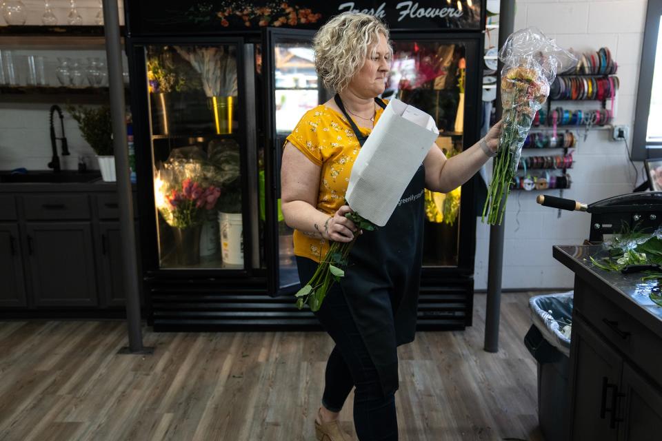 Jenn Drake pulls flowers out of the cooler to create bouquets for Mother's Day in her flower shop.