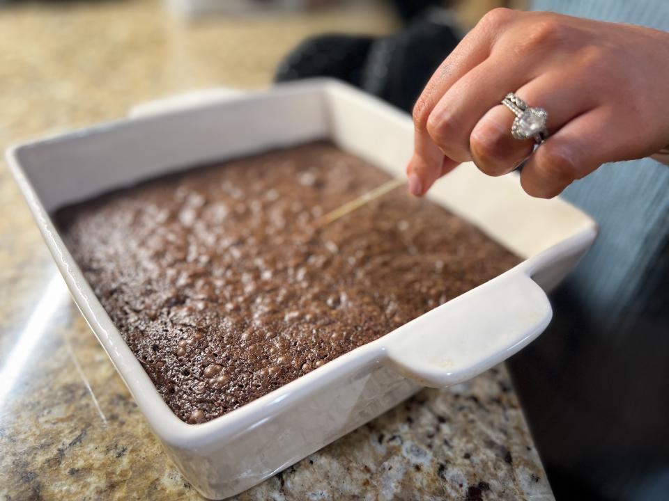 hand about to poke a toothpick into a baked pan of brownies