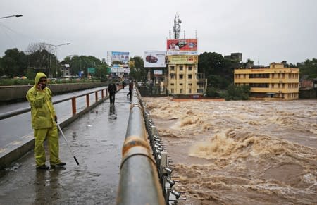 A policeman stands on a bridge as houses are seen submerged in the waters of overflowing river Godavari after heavy rainfall in Nashik