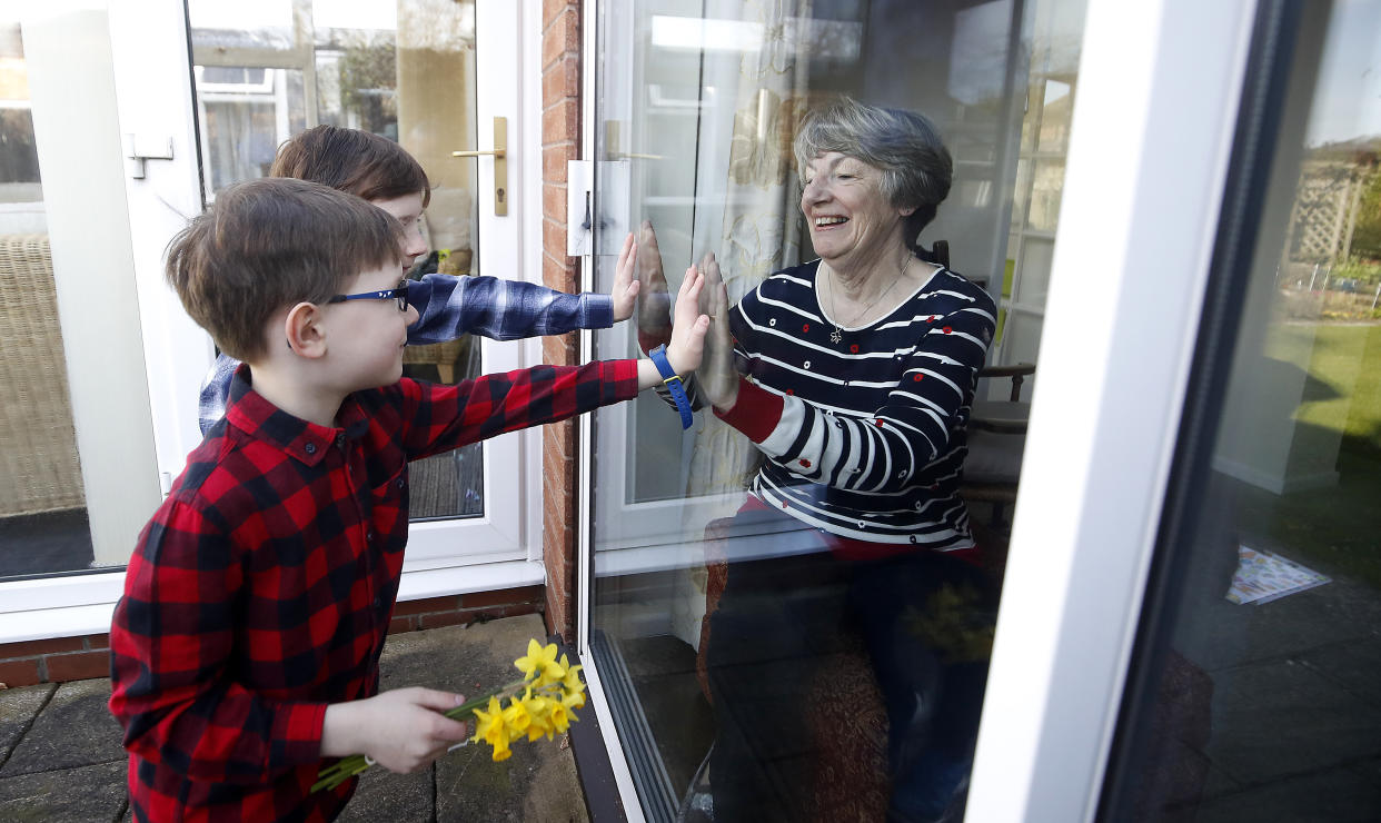 Ben and Isaac talk to their grandmother Sue through a window, as she and her husband Alan self-isolate due at their home in Knutsford, Cheshire. (Photo by Martin Rickett/PA Images via Getty Images)