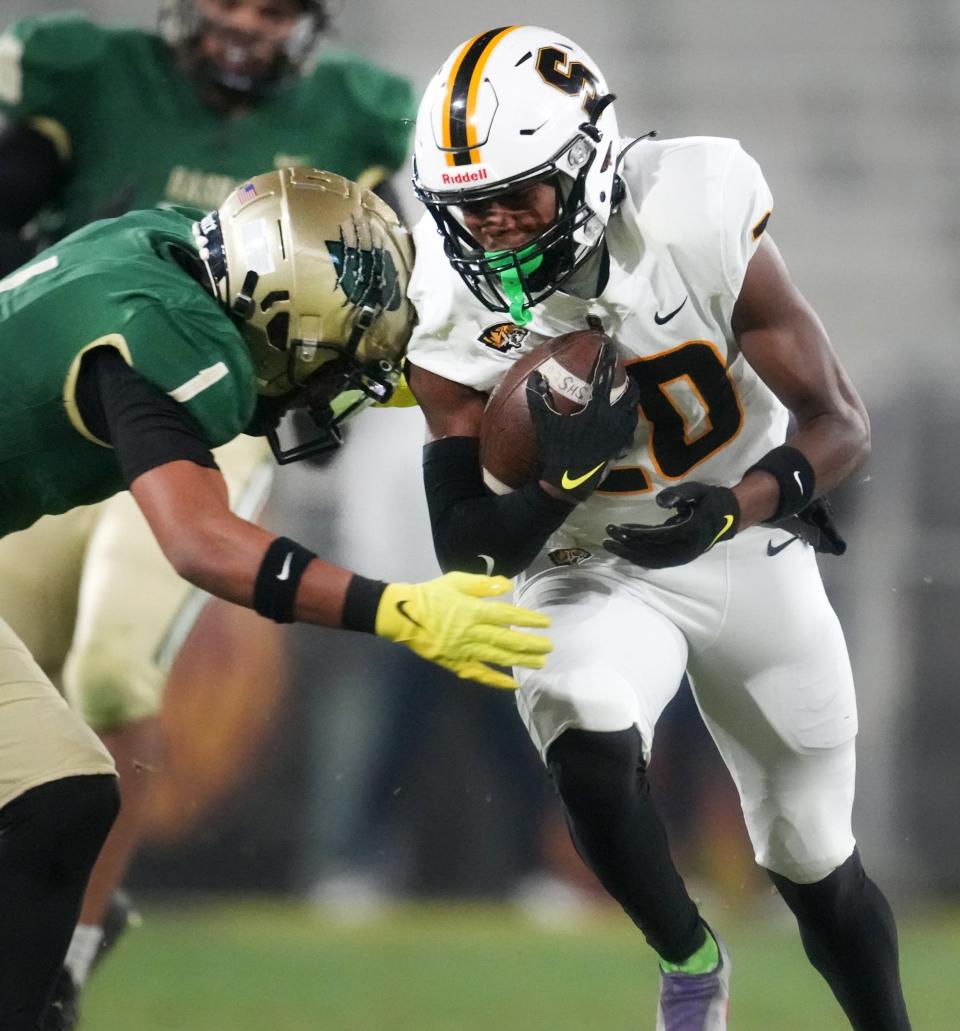 Saguaro's Dajon Hinton (20) runs with the ball as Basha's Miles Lockhart (1) comes in for the tackle during their Open Division State Championship at ASU Sun Devil Stadium in Tempe on Dec. 10, 2022.