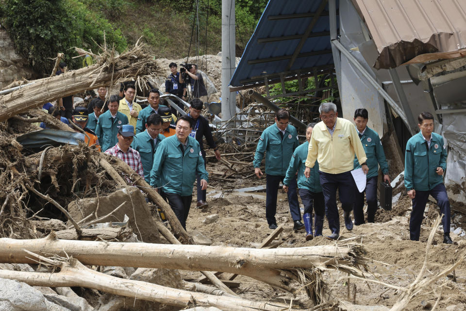 South Korean President Yoon Suk Yeol, third from left, looks around a flood damaged area in Yecheon, South Korea, Monday, July 17, 2023. Heavy downpours lashed South Korea a ninth day on Monday as rescue workers struggled to search for survivors in landslides, buckled homes and swamped vehicles in the most destructive storm to hit the country this year. (Jin Sung-chul/Yonhap via AP)