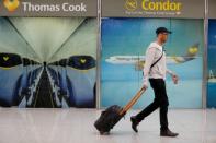 A passenger passes Thomas Cook banners at Mallorca Airport as an announcement is expected on the tour operator