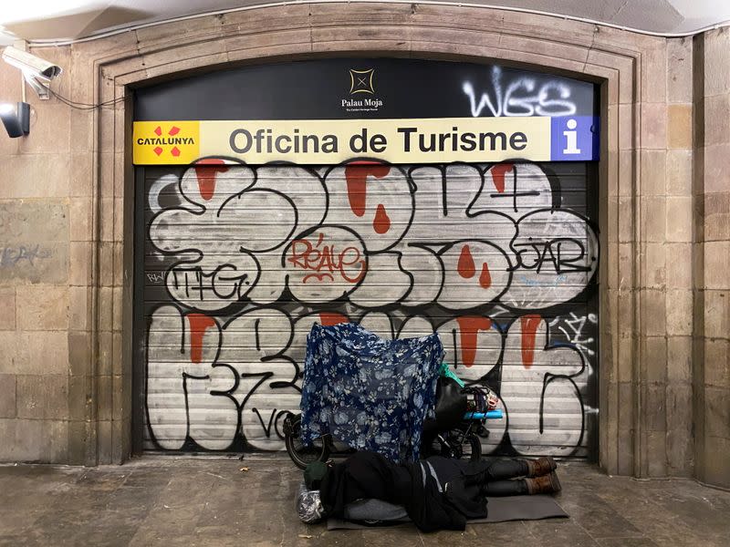 Una persona sin hogar duerme a la entrada de una oficina de turismo cerrada en Barcelona, España, el 22 de octubre de 2020