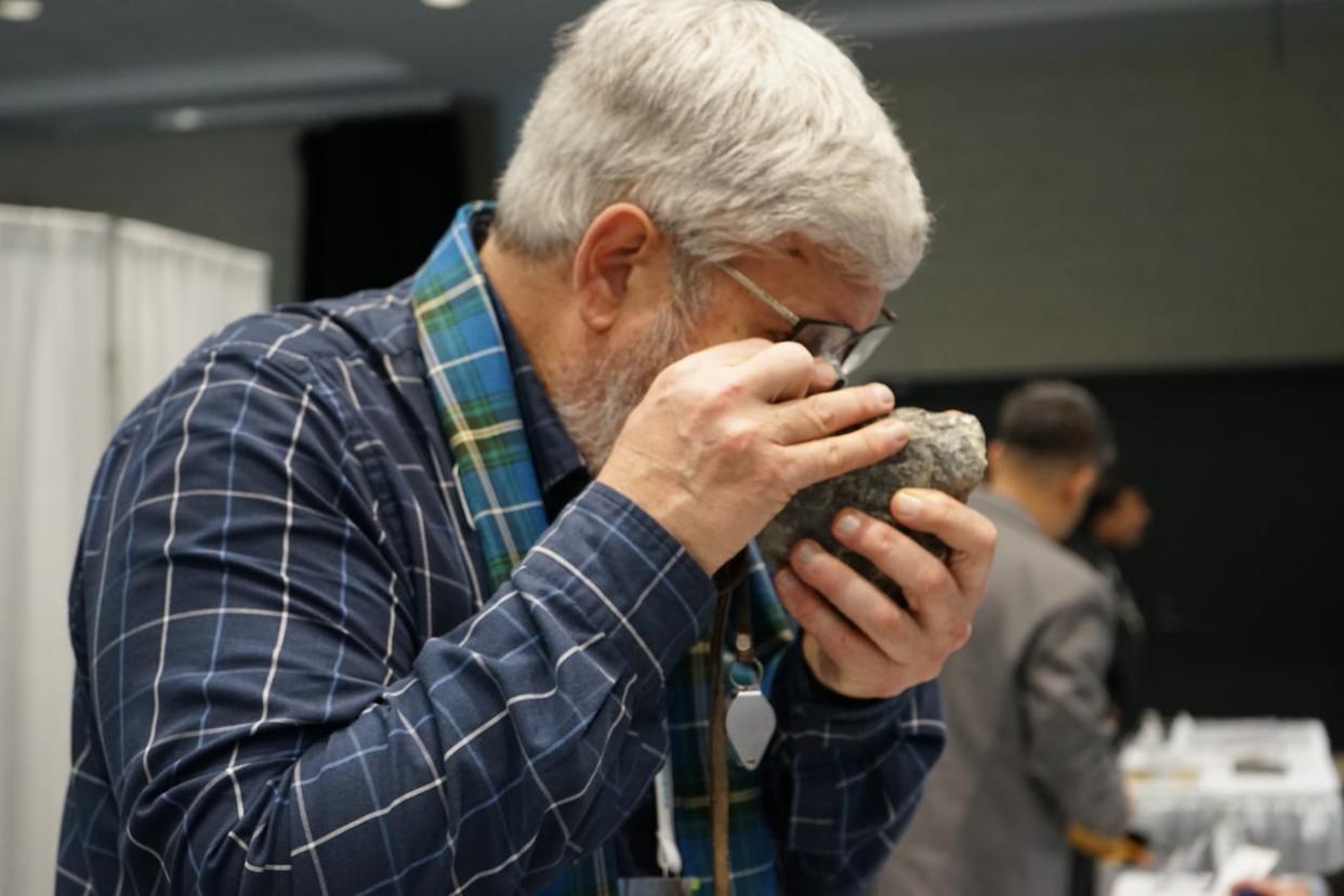 A mining explorer studies a rock during the Prospectors & Developers Association of Canada 2024 convention. (Aya Dufour/CBC - image credit)